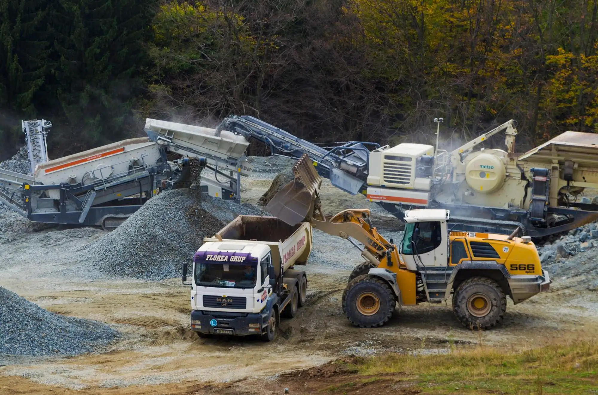 Autobasculantă Florea Grup încărcată cu agregate lângă stația mobilă de concasare din carieră