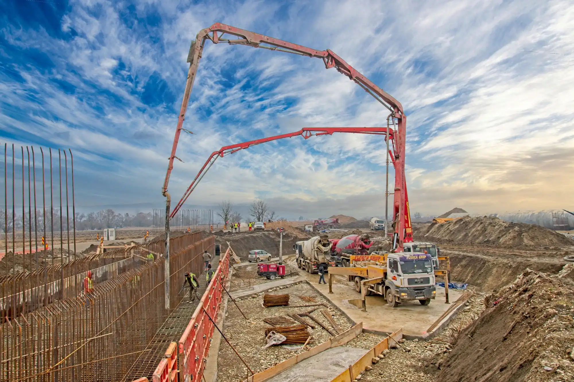 Pompă de beton cu brațul desfăcut pe un șantier, sub cer înnorat