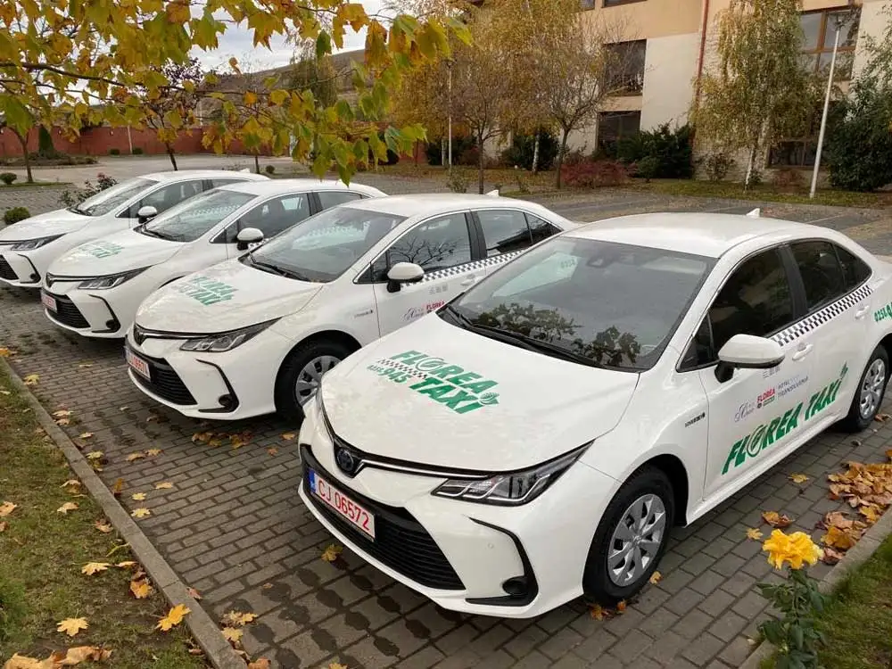 Autoturisme hibride Florea Taxi parcate în fața unei clădiri