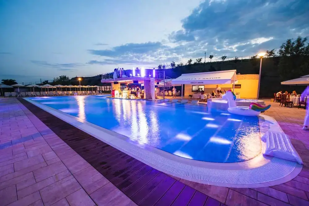 Piscina Astoria Pool Park iluminată, cu barul în fundal