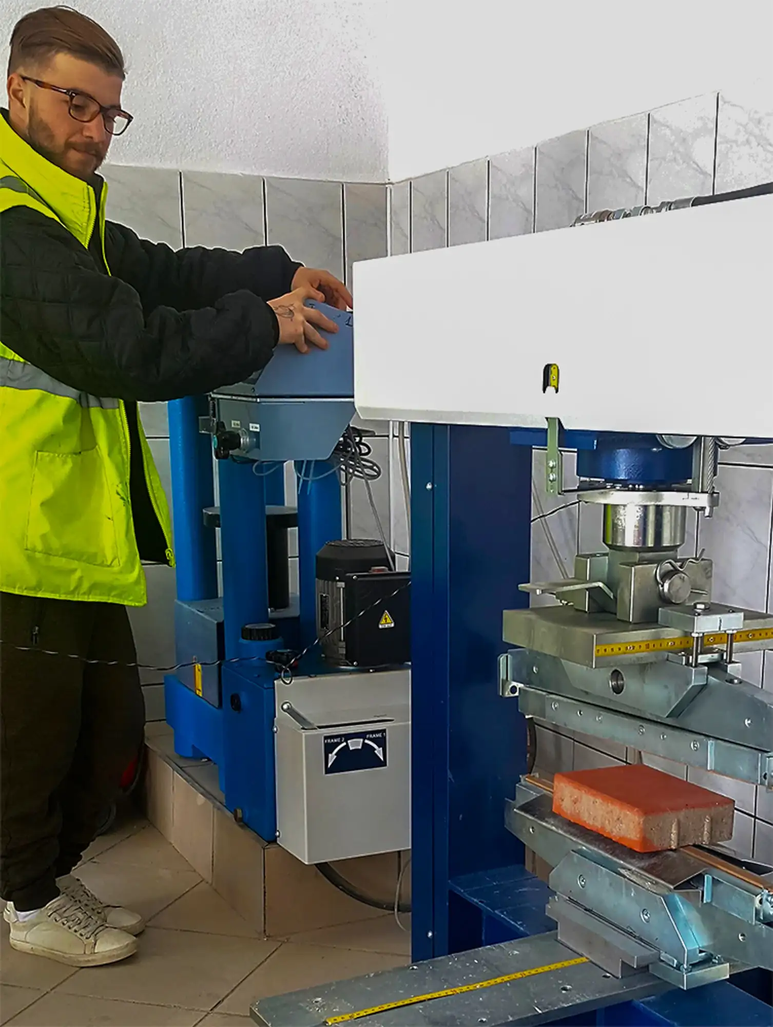 Specialist de laborator lângă o presă hidraulică de testare a rezistenței materialelor