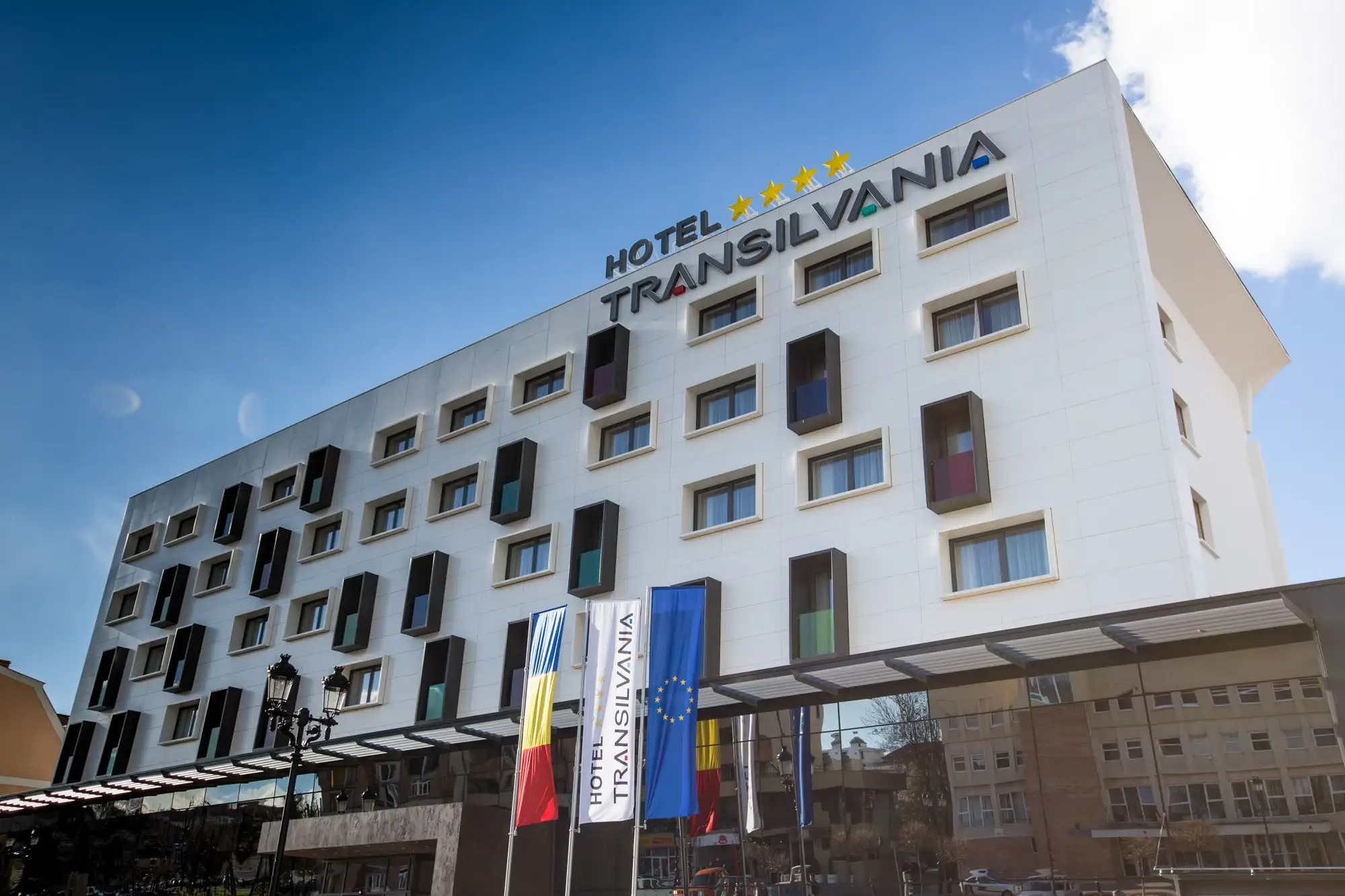 Fațada Hotelului Transilvania din Alba Iulia, cu ferestre colorate și steaguri